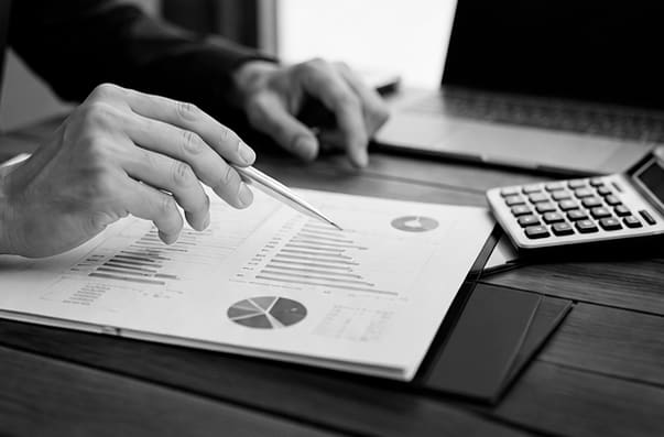 Advogado analisando gráficos e cálculos de um contrato bancário com caneta e calculadora — análise técnica da dívida