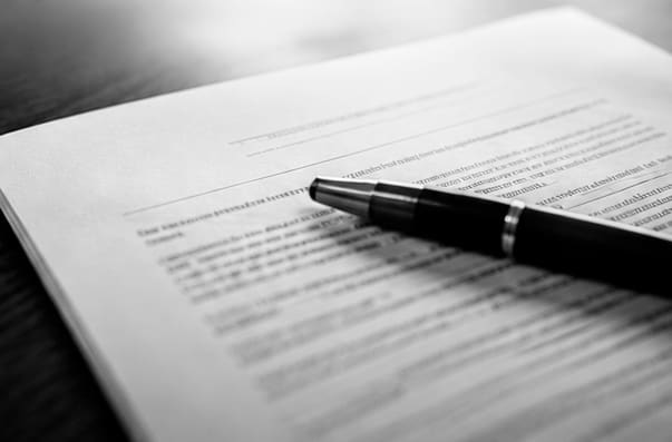 Caneta sobre as cláusulas de um contrato de refinanciamento bancário
