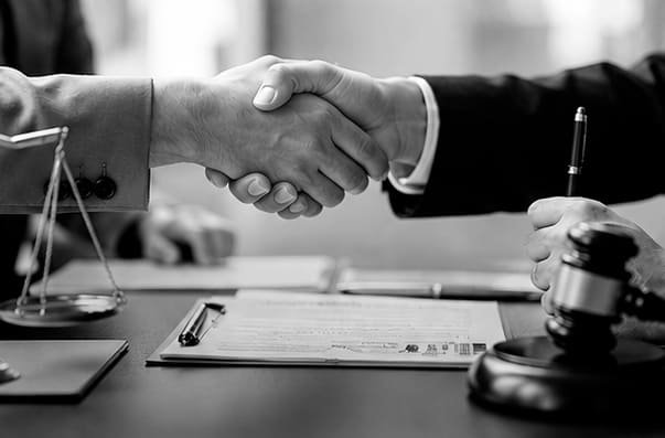 Aperto de mãos entre advogado e representante do banco, com balança da justiça e martelo — negociação de dívida bancária empresarial
